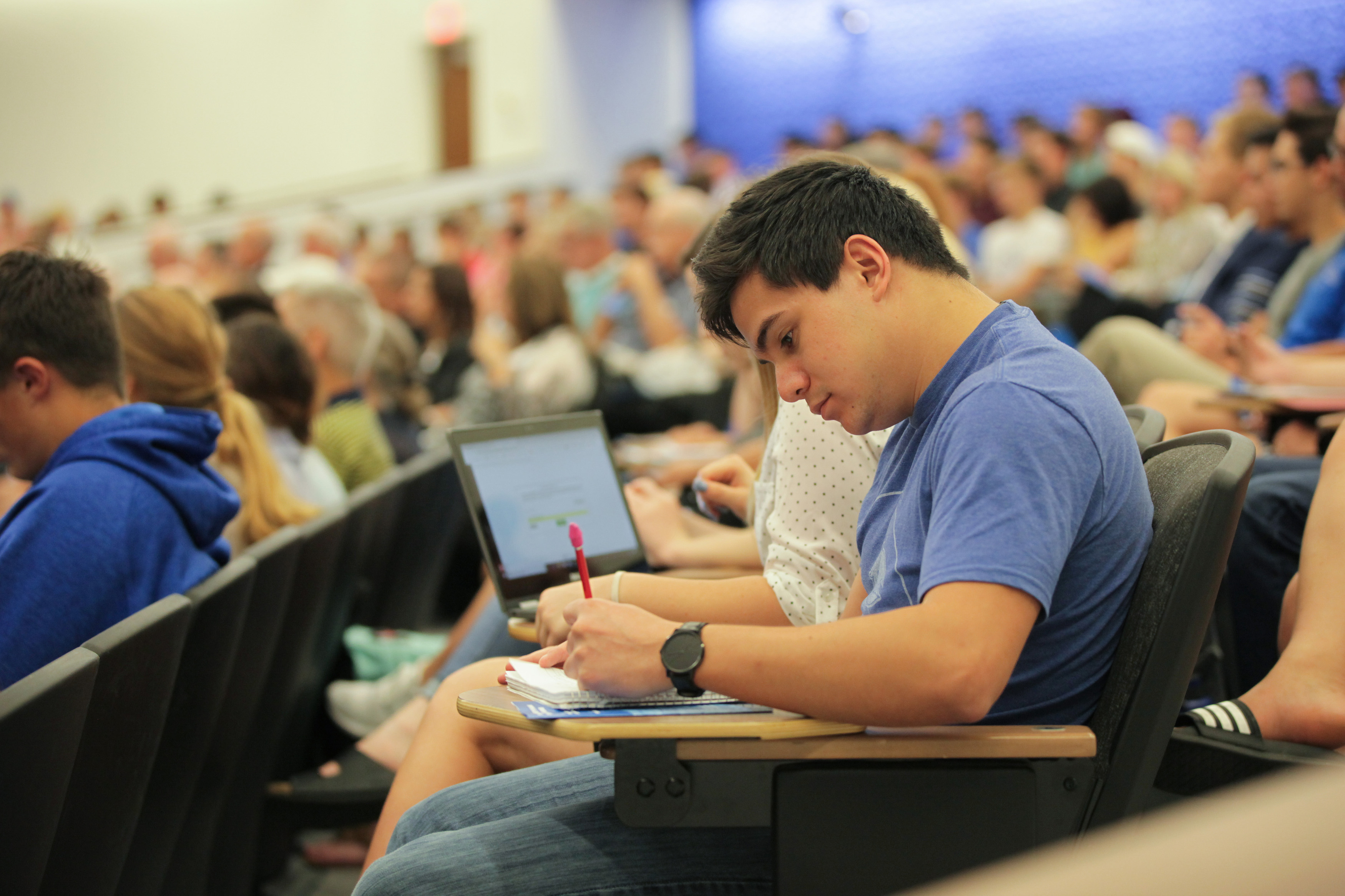 A student takes notes at a desk in the Capitol Federal Hall auditorium.