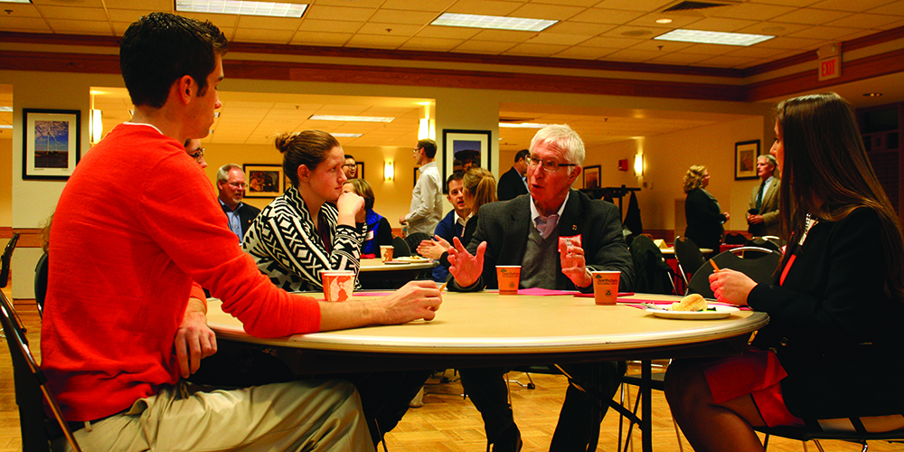Alumnus Mike Thompson talks with a table of students.
