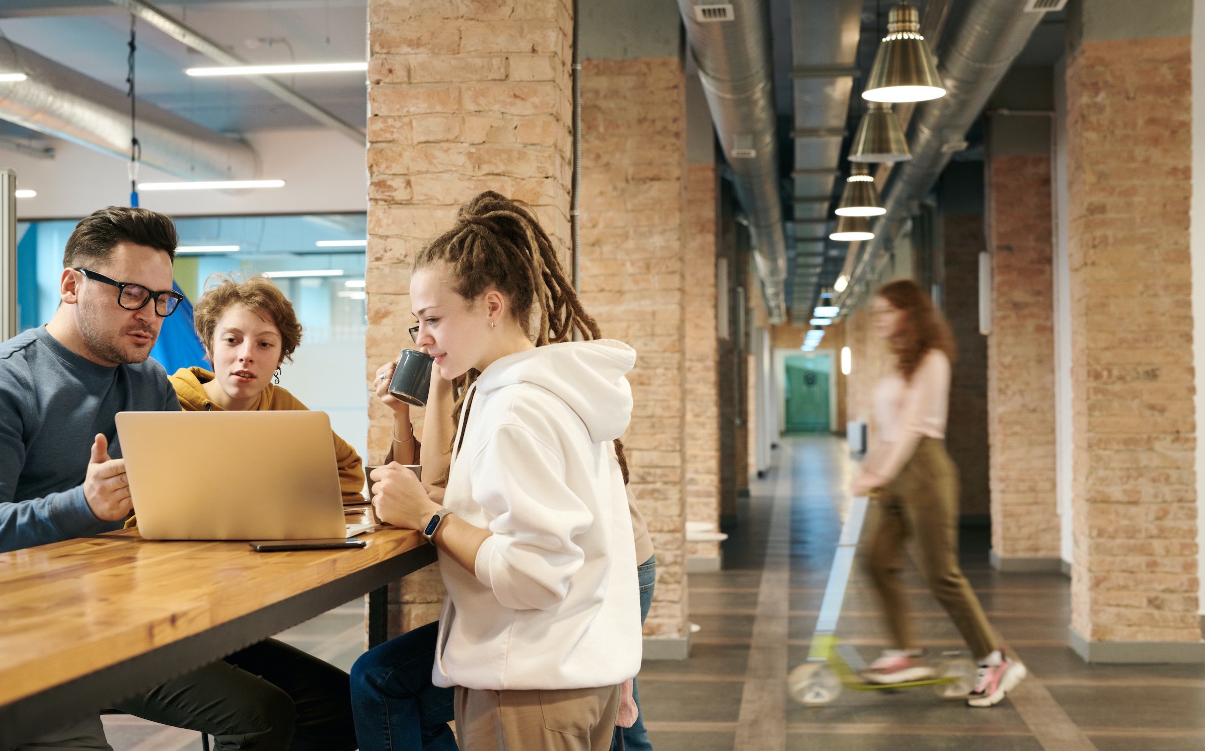 Coworkers talk while gathered around a laptop.