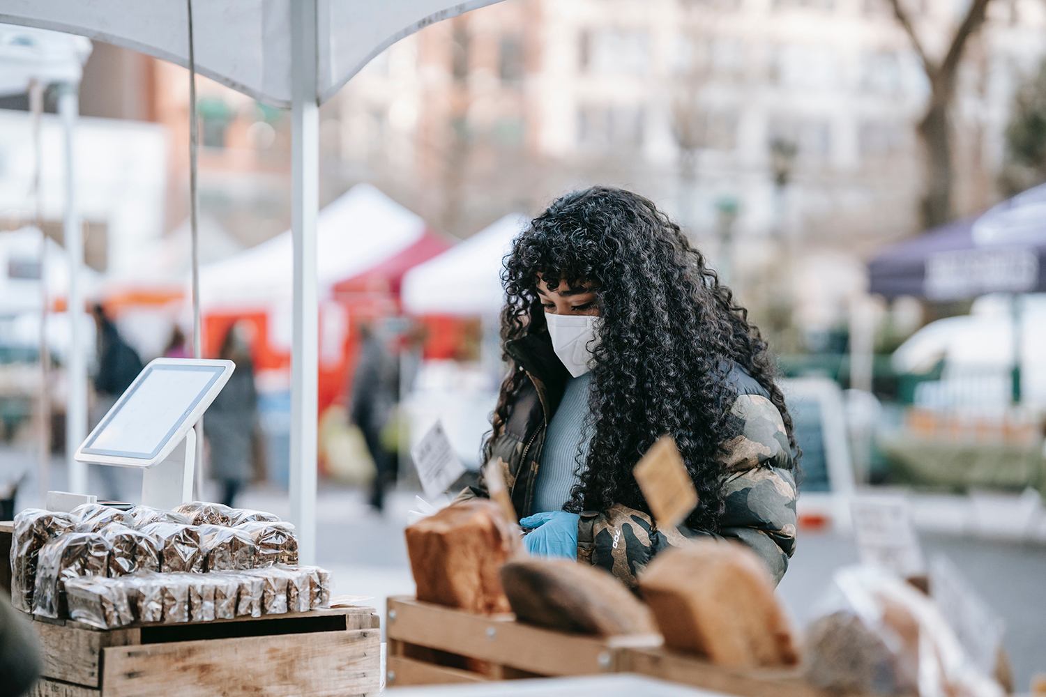 A woman wearing a medical mask shops at a farmers' market