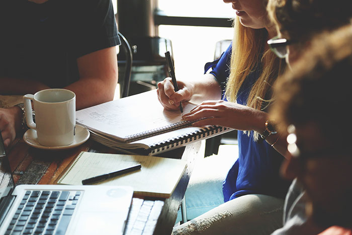 A team collaborates as a woman writes in a notebook