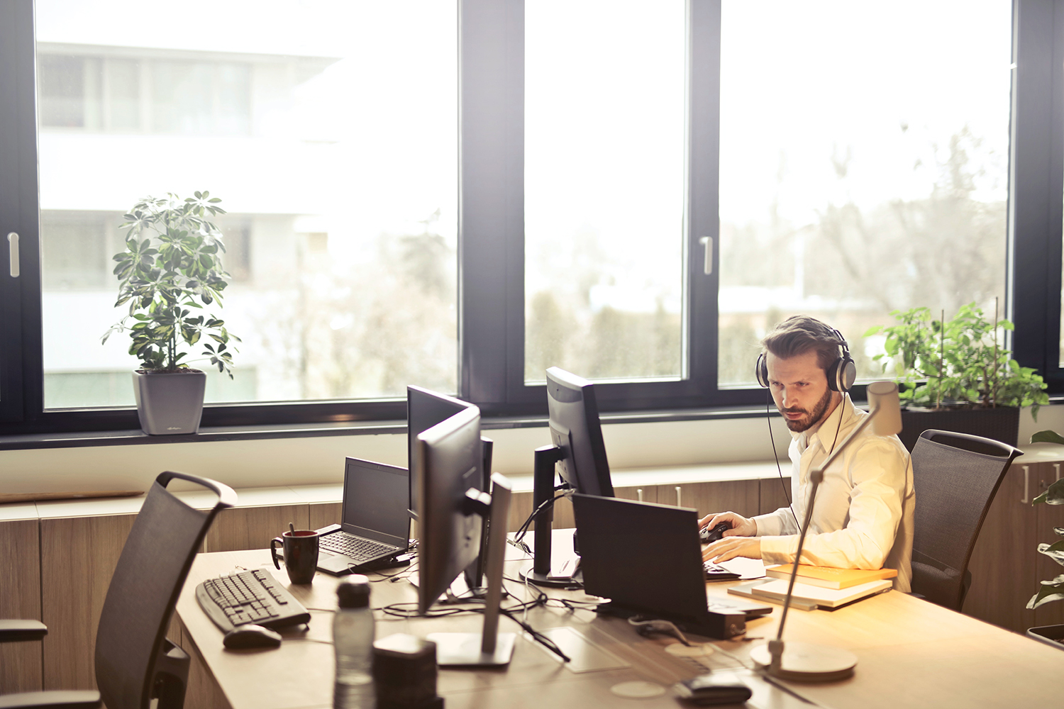 A man works at a computer while wearing headphones