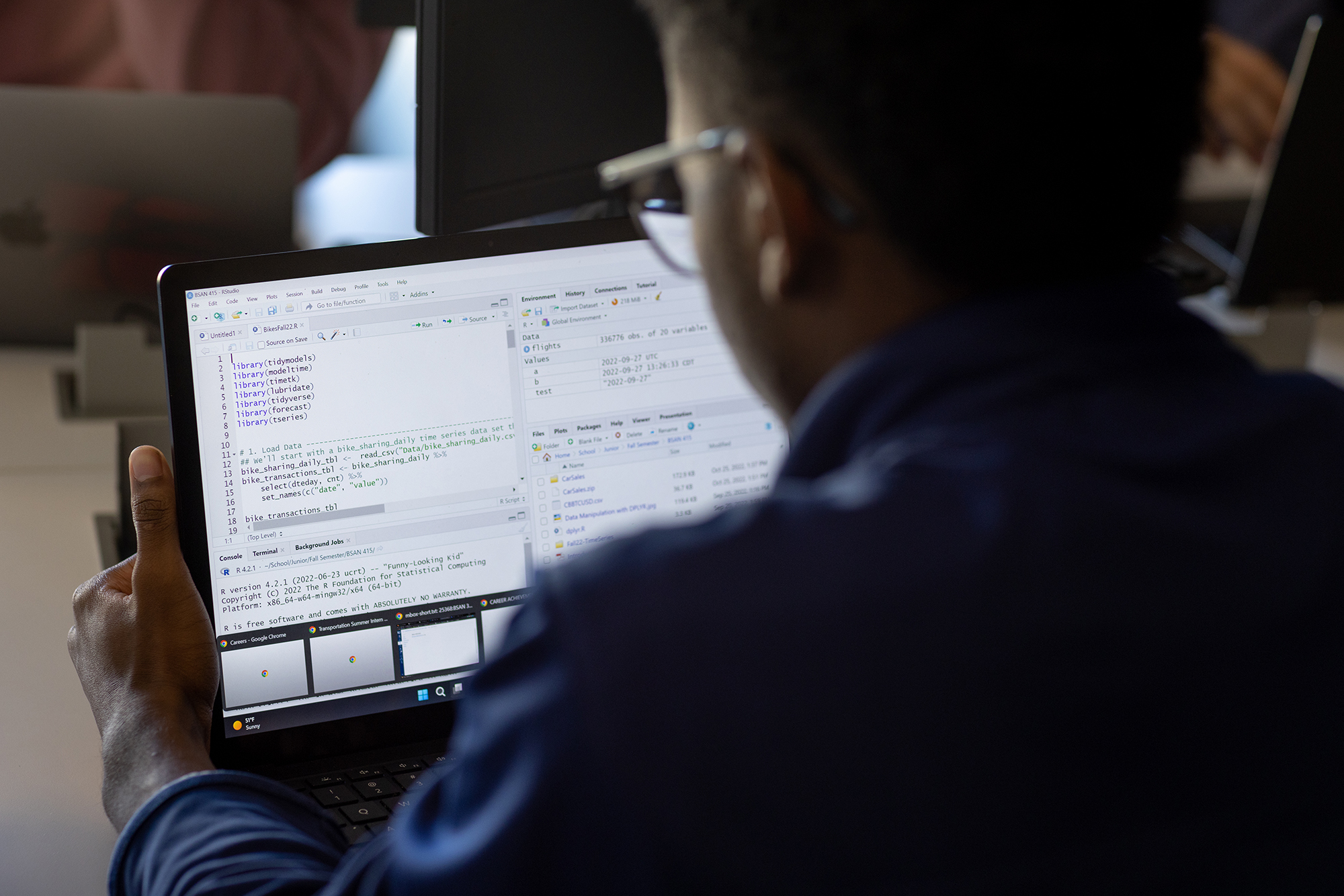 A student works on a laptop that displays code