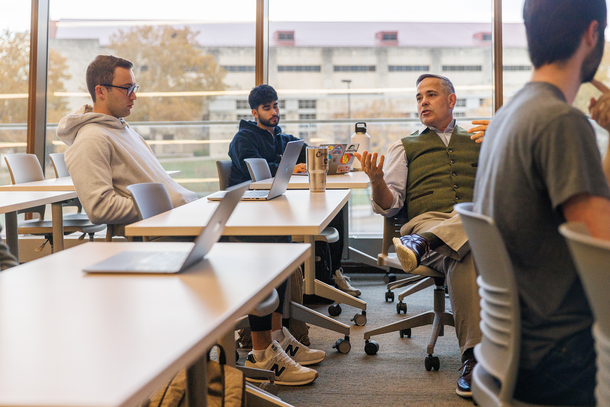 Faculty member Steve Leonard speaks with students while seated in a MGMT 498 course