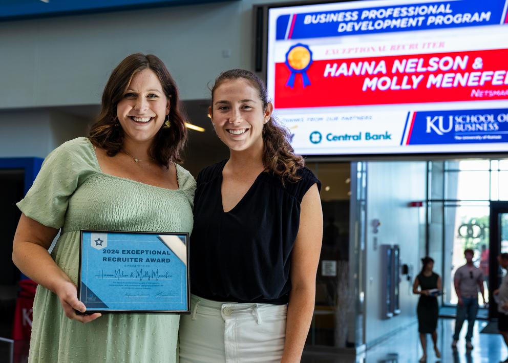 Two people hold the 2024 Exceptional Recruiter Award from the EY Business Professional Development Program